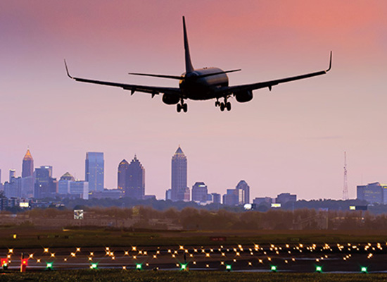 Plane landing on a runway with skyline in background