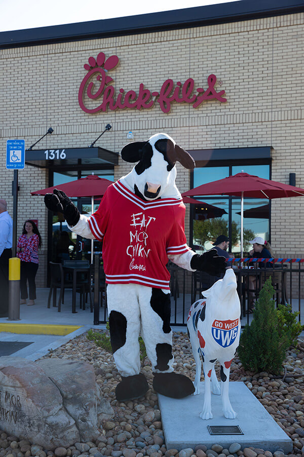 Chick-fil-A cow mascot stands with wolf