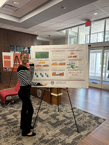 Moise poses in the lobby of RCOB with a poster board