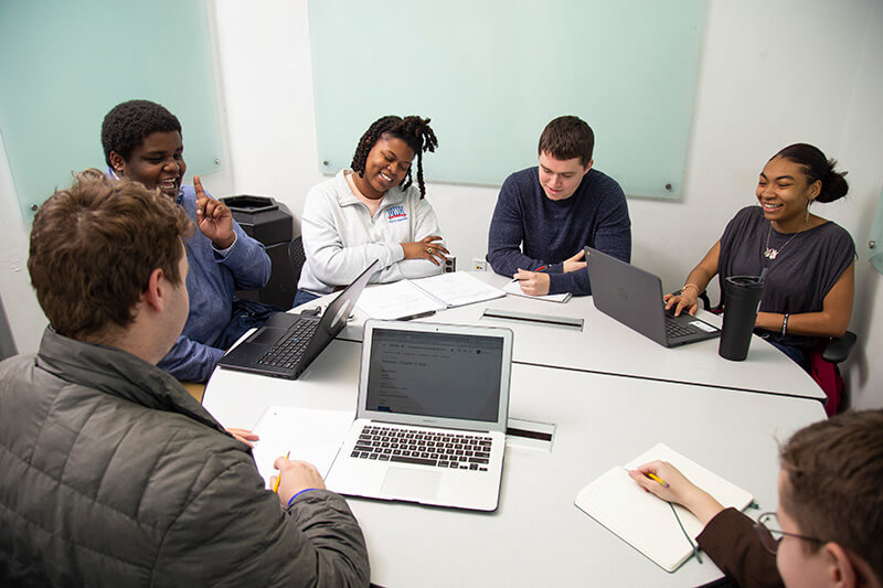 Students sitting around a table on laptops