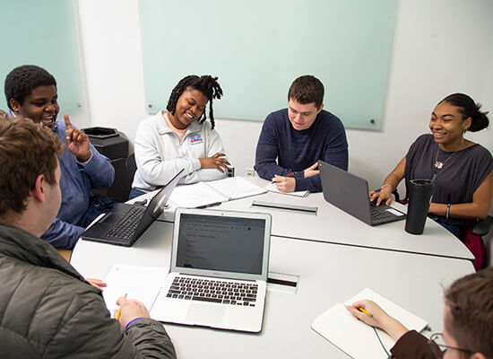 Students sitting around a table on laptops