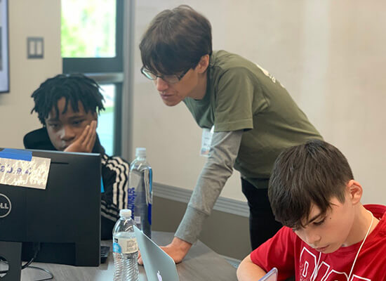 A UWG professor helps kids on laptops
