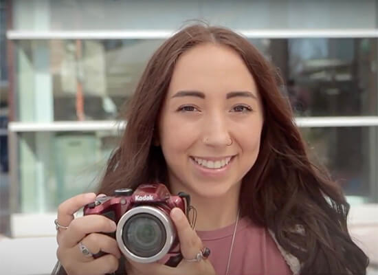 Smiling female student holding a camera