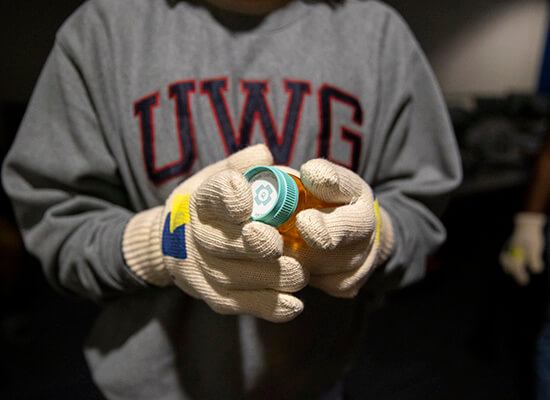 A UWG student demonstrates dementia simulation tools such as thick gloves.

