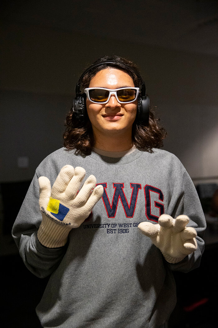 A UWG student demonstrates dementia simulation tools such as dark glasses and thick gloves.