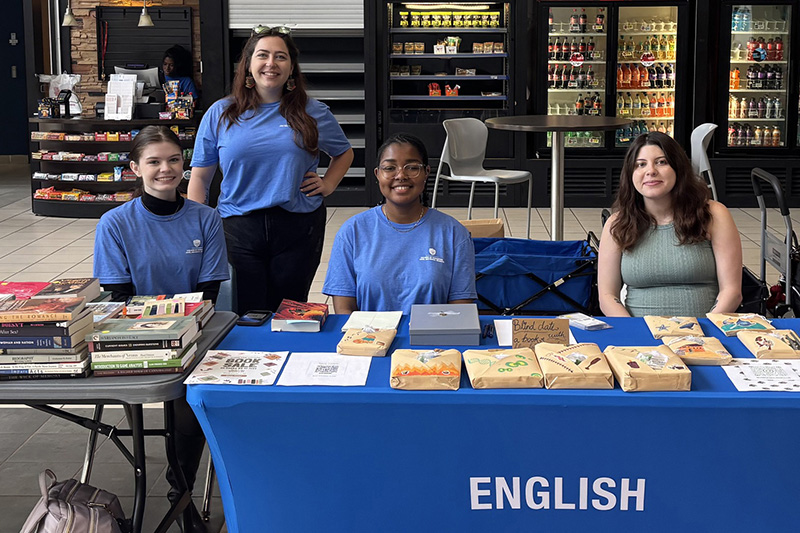 Four UWG students sitting at a table at the 2025 Book Fair