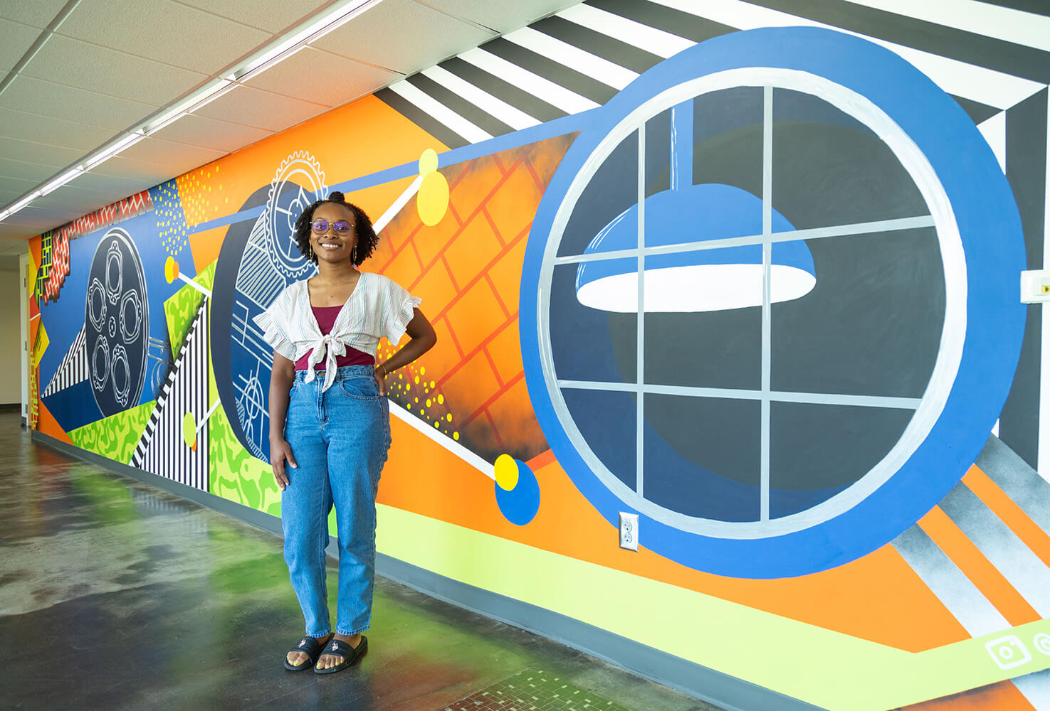 woman standing in front of a mural she painted
