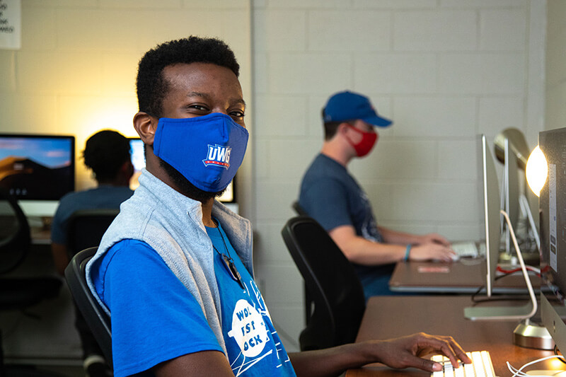Student wearing a mask and sitting at a computer 