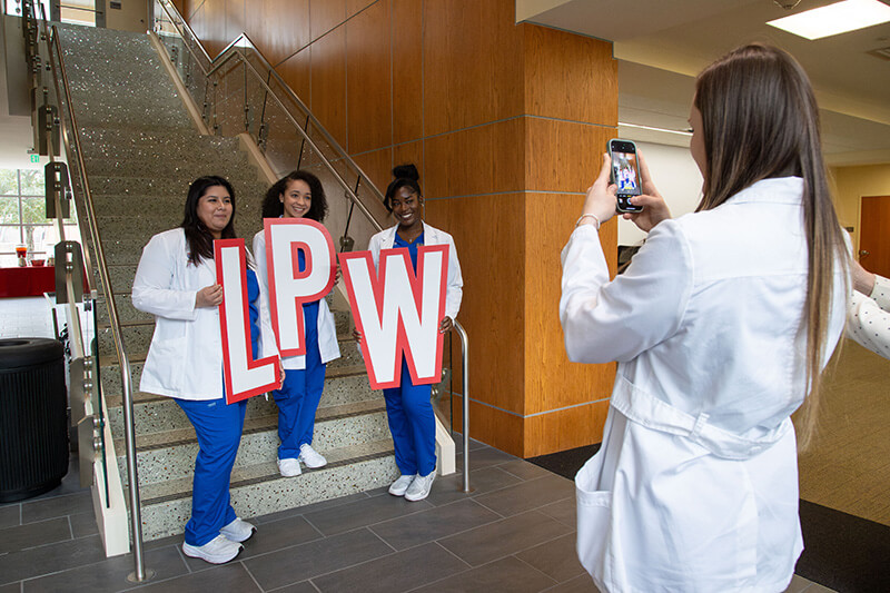 Someone taking a photo of three UWG nursing students holding the letters LPW