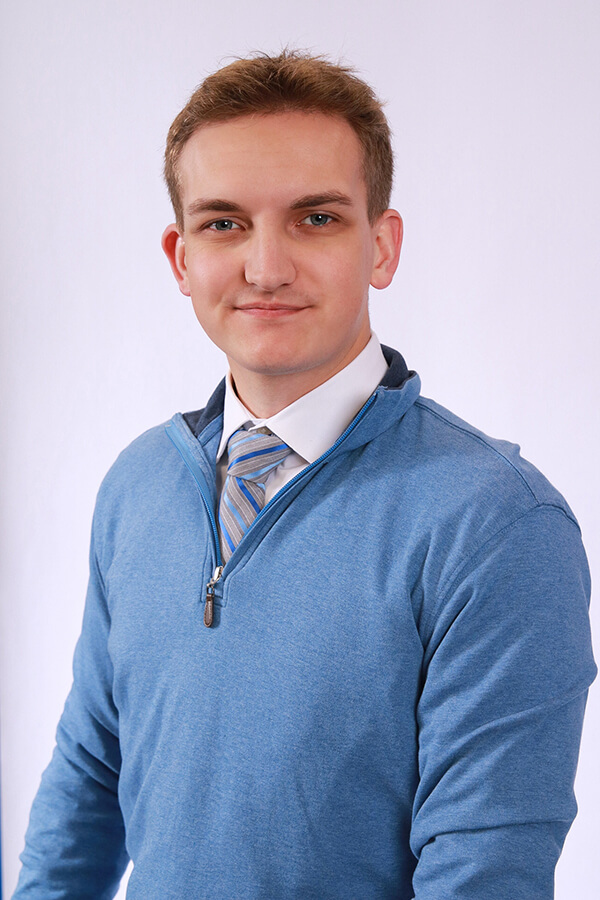 Zachary Tafelski poses for a portrait in a blue sweater
