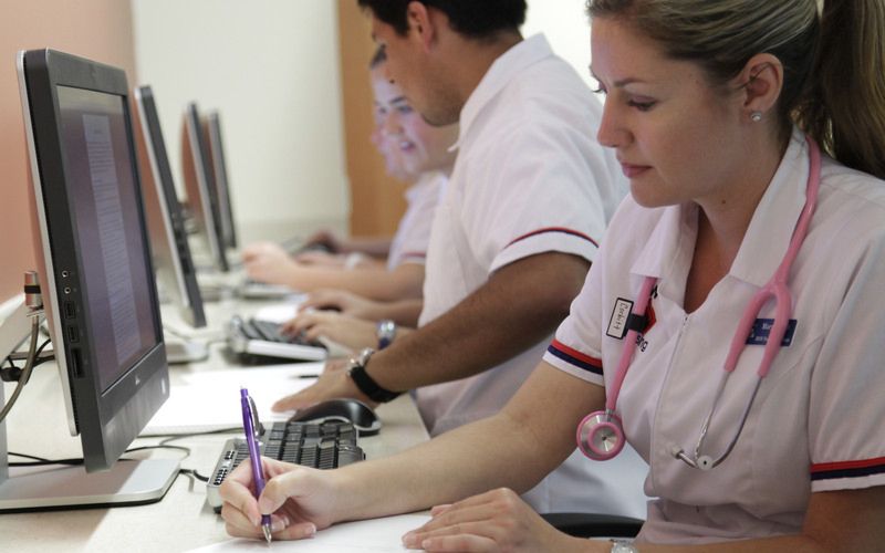 a nursing student taking notes while at a computer