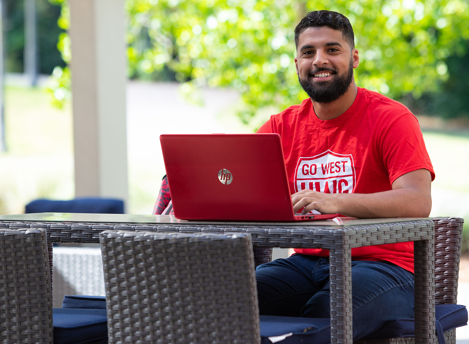 male student working on a laptop on the Campus Center Back Patio