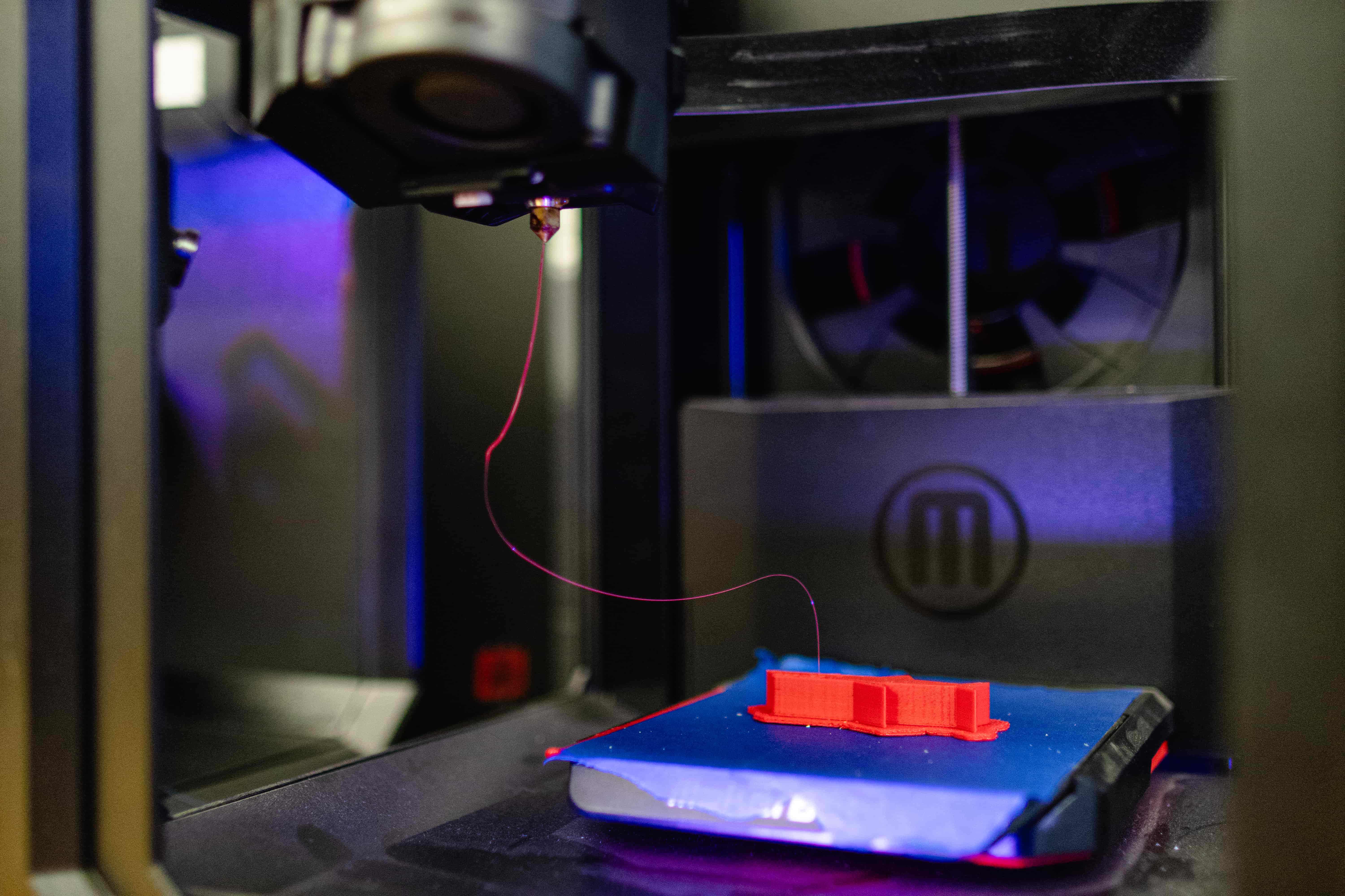 Close up of a 3D printer pushing out a plastic strand as it completes a project.