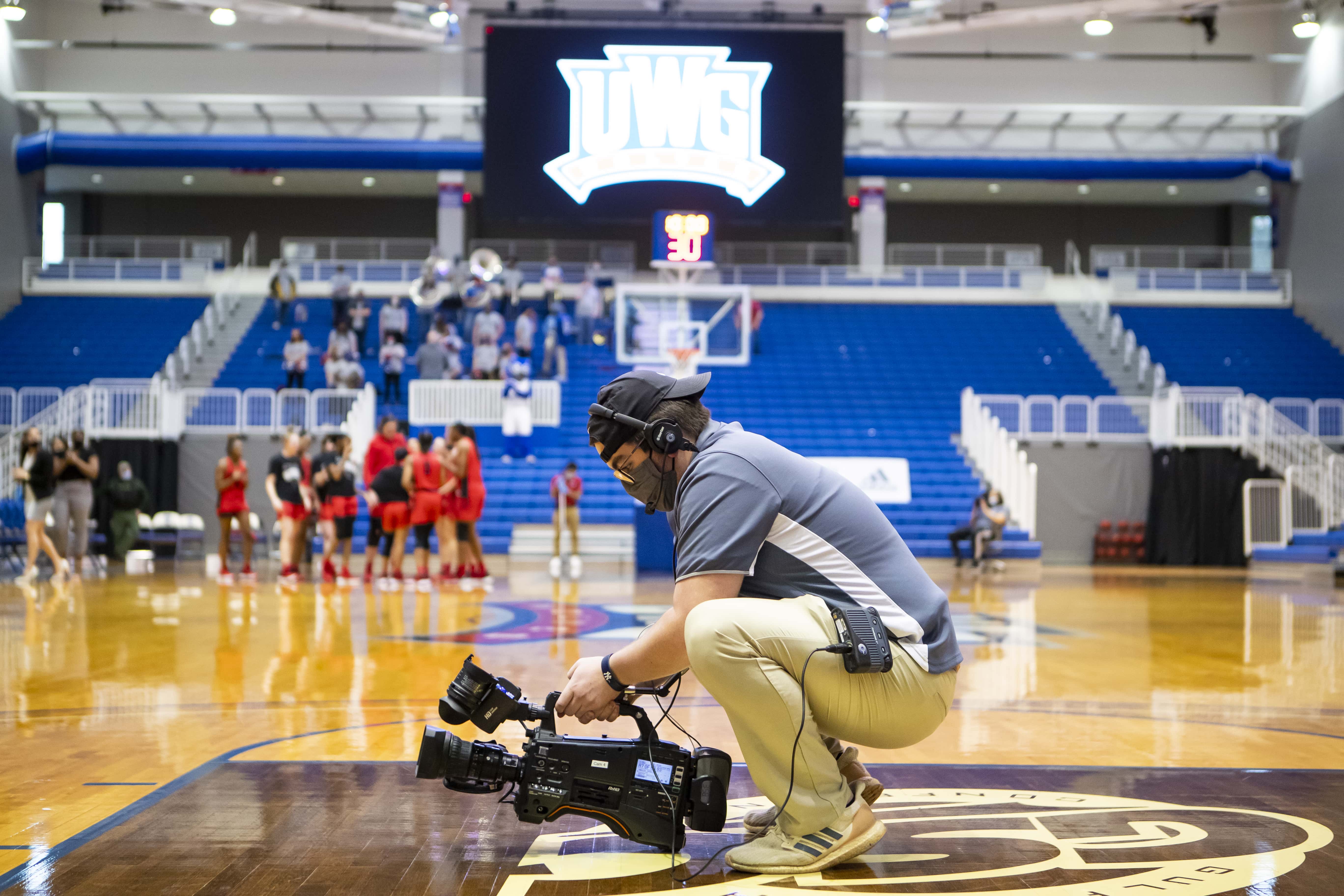 Guy holding camera in middle of basketball court.