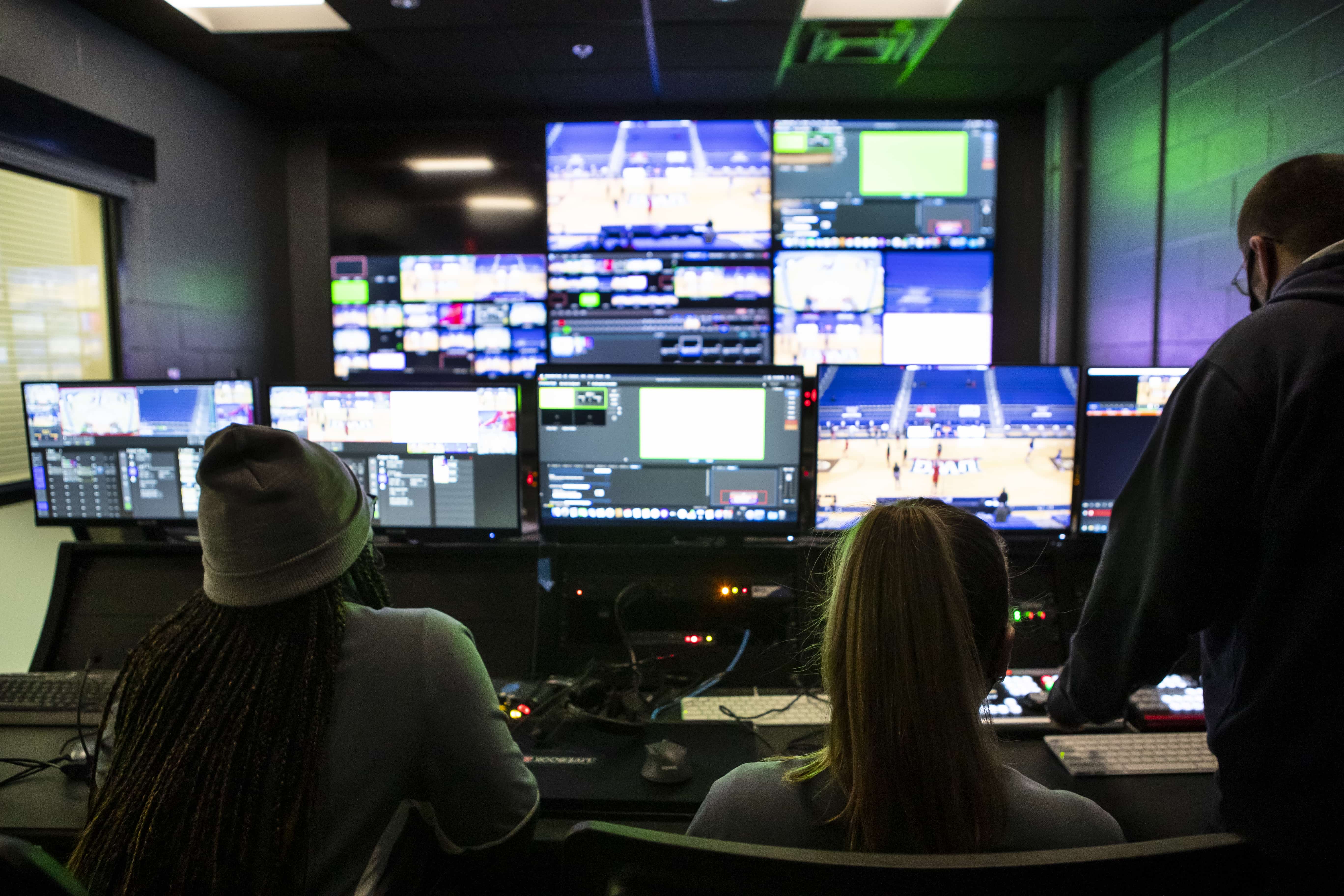 Production students sitting in front of a group of digital screens at the control room.