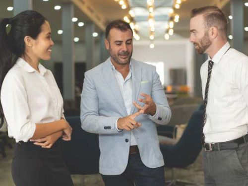 Three professionally dressed individuals conversing in lobby area