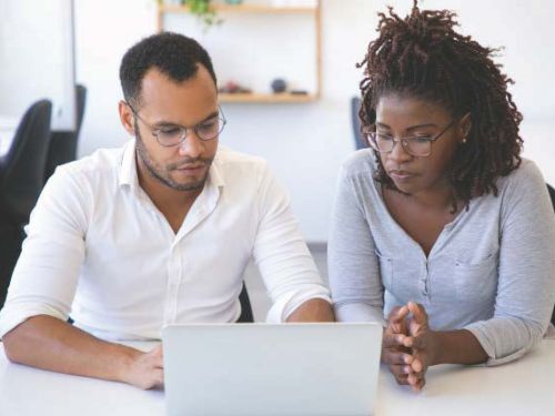 Two individuals looking at a laptop screen