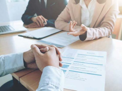 Three individuals sitting at a small conference table