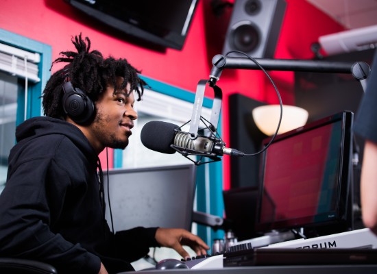 male student working in a radio station booth