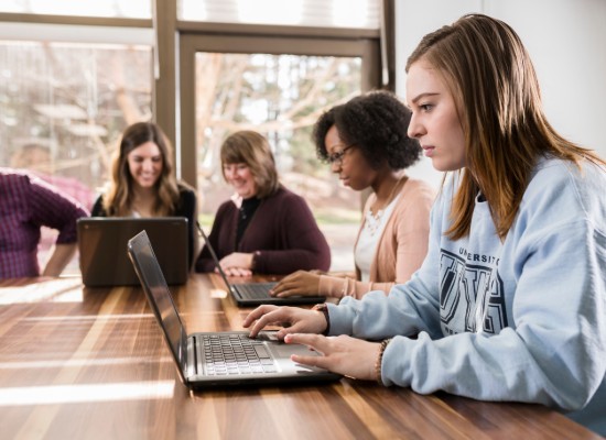 students working on laptops at a long table