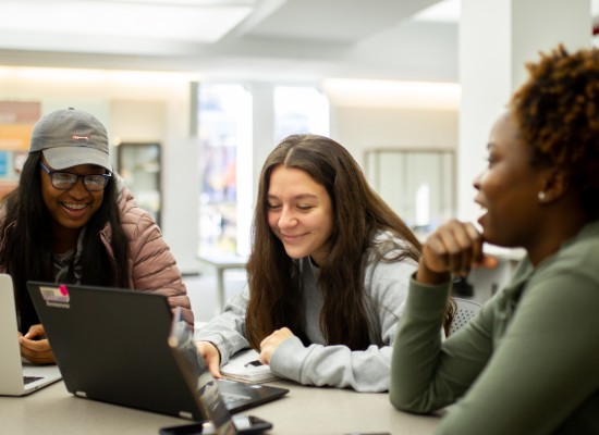 three students working at a laptop