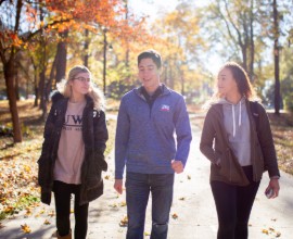 Three students walking outside in the fall.