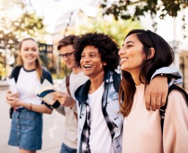 Four students outside with arms around each other.