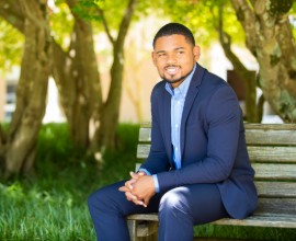 Student sitting on a bench wearing a suit.