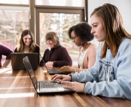 students working at a table with computers.