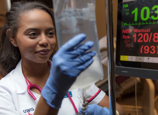 Nursing student looking at and setting up and IV bag.