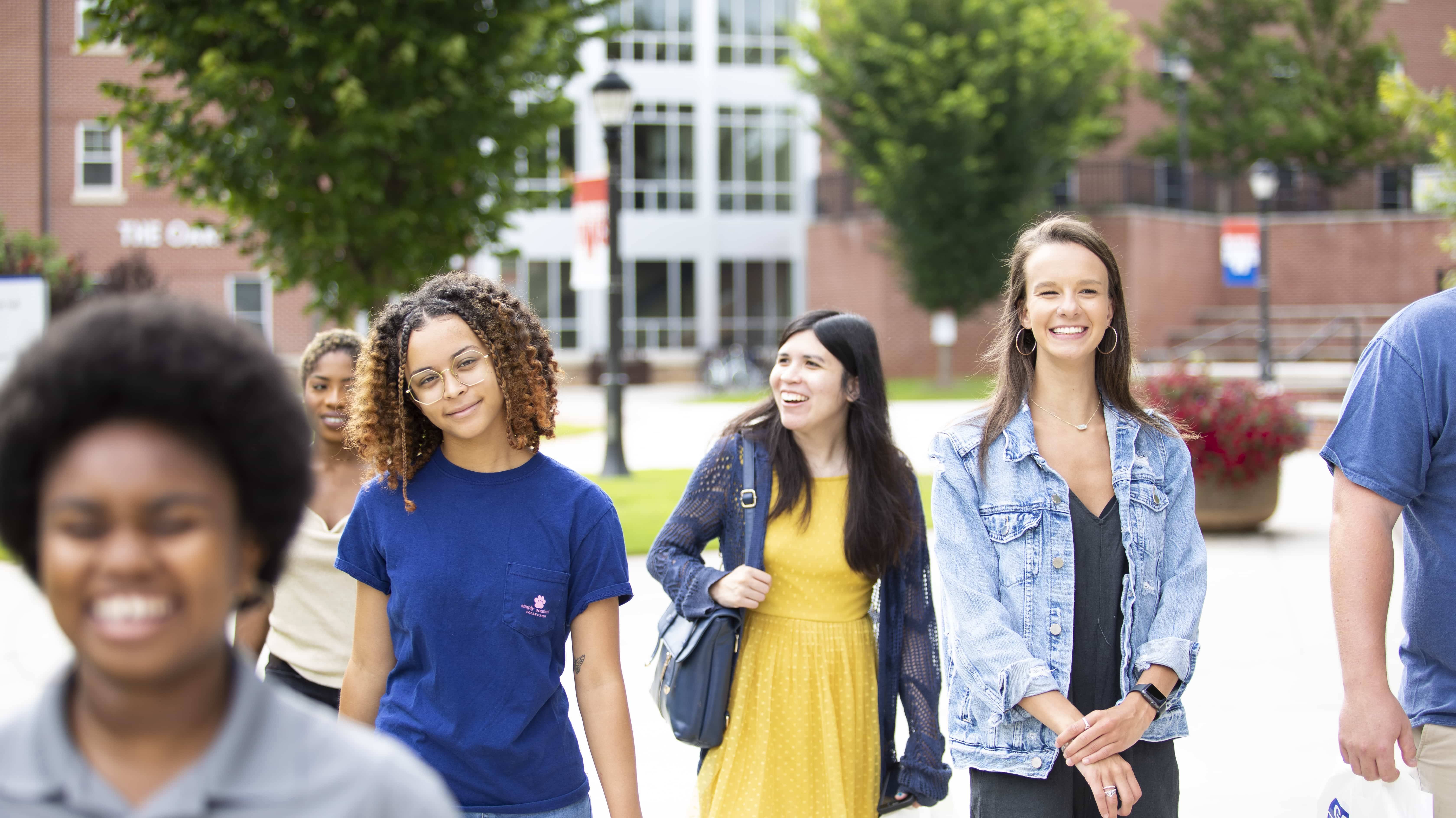 Student walking and smiling on campus.