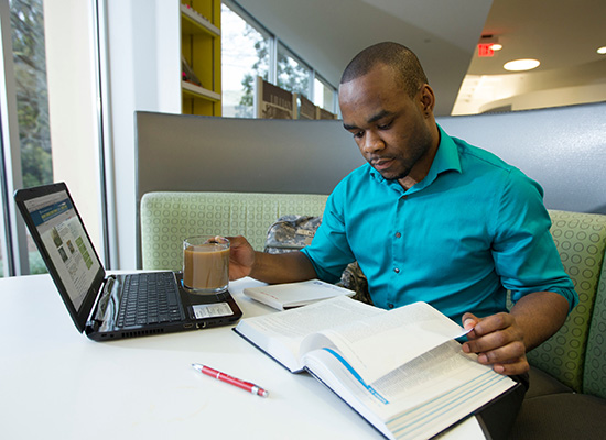 UWG student working on his computer in the library.