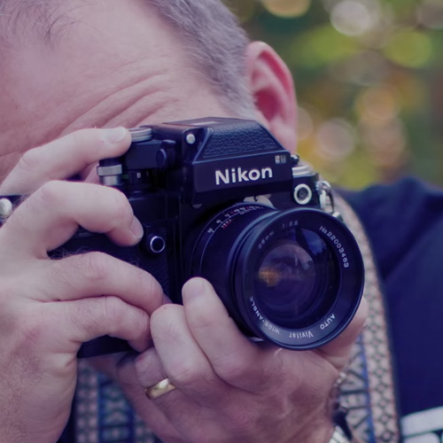 Man looking through a DSLR camera.