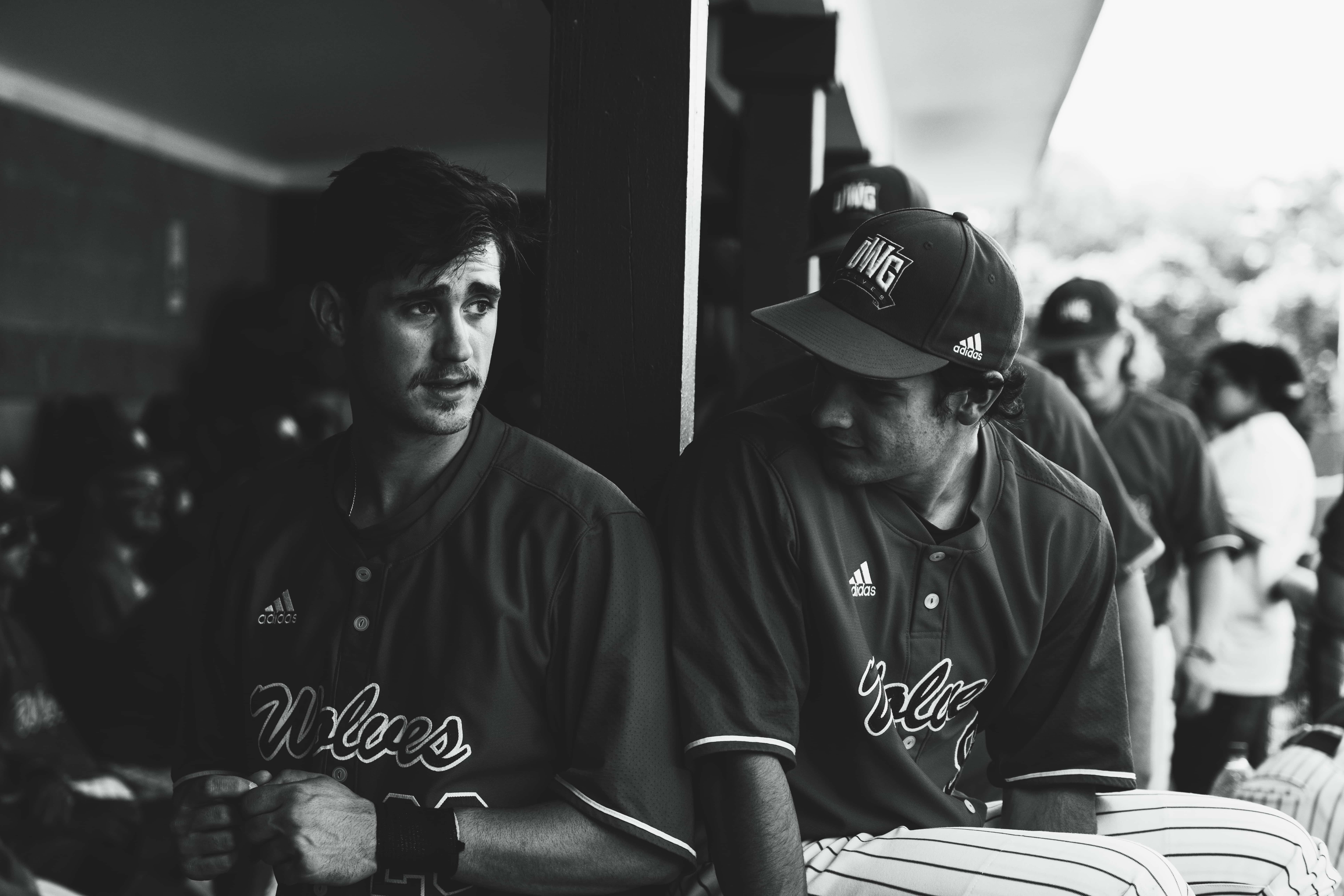 Baseball players sitting together in the dugout.