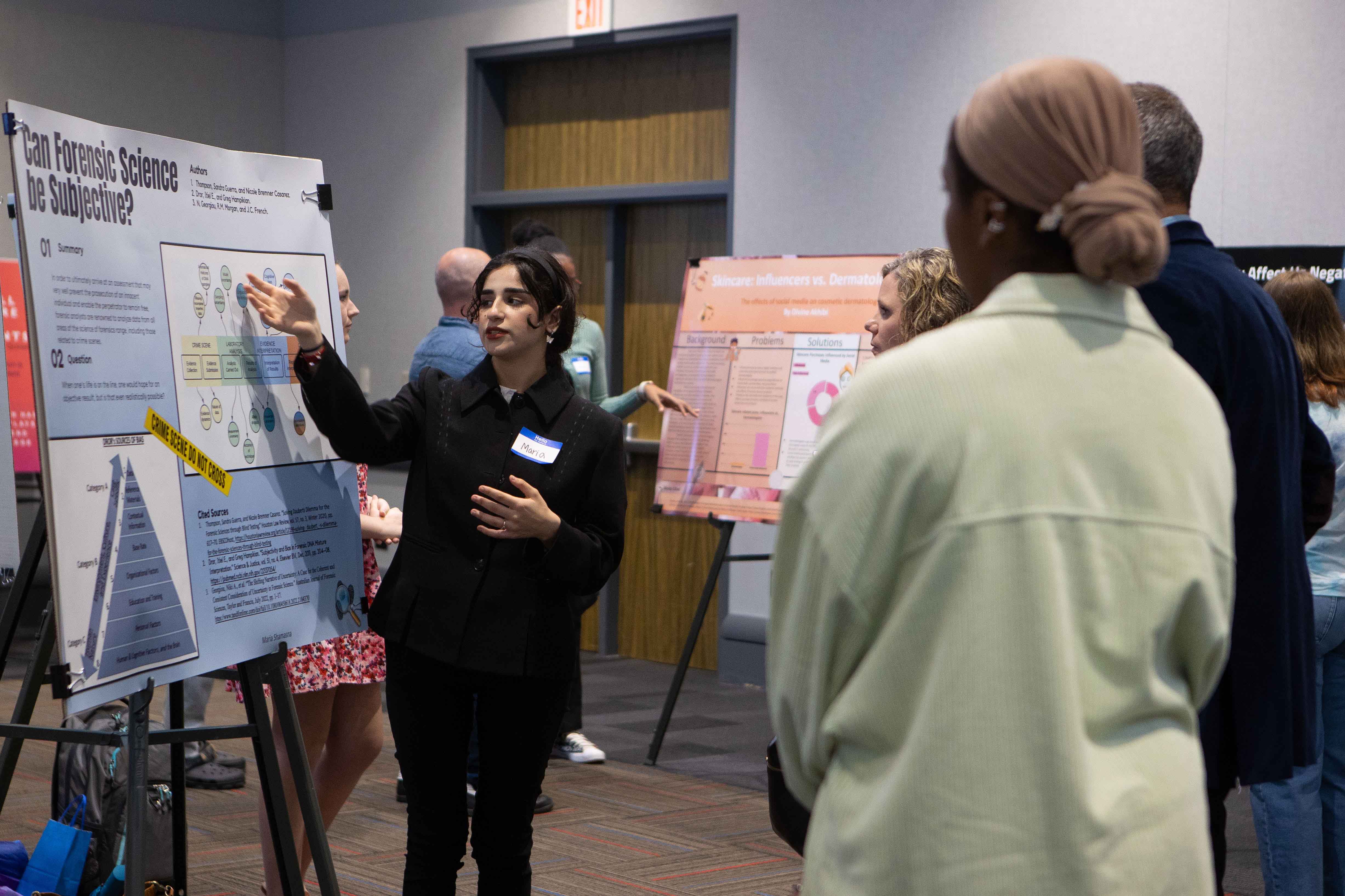 Student discussing project with guests at Scholars Day