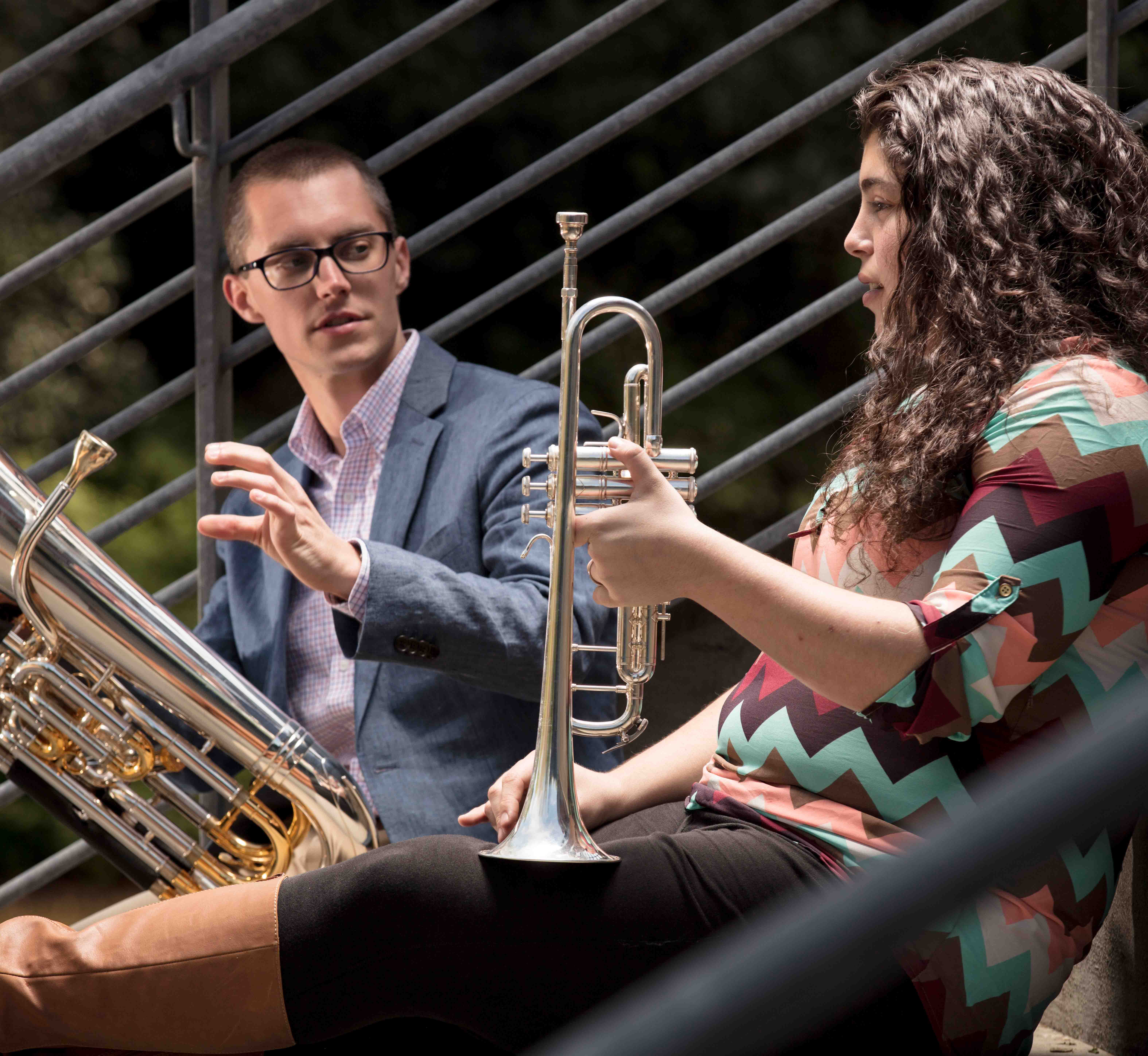 Two brass musicians sitting on the TLC stairs