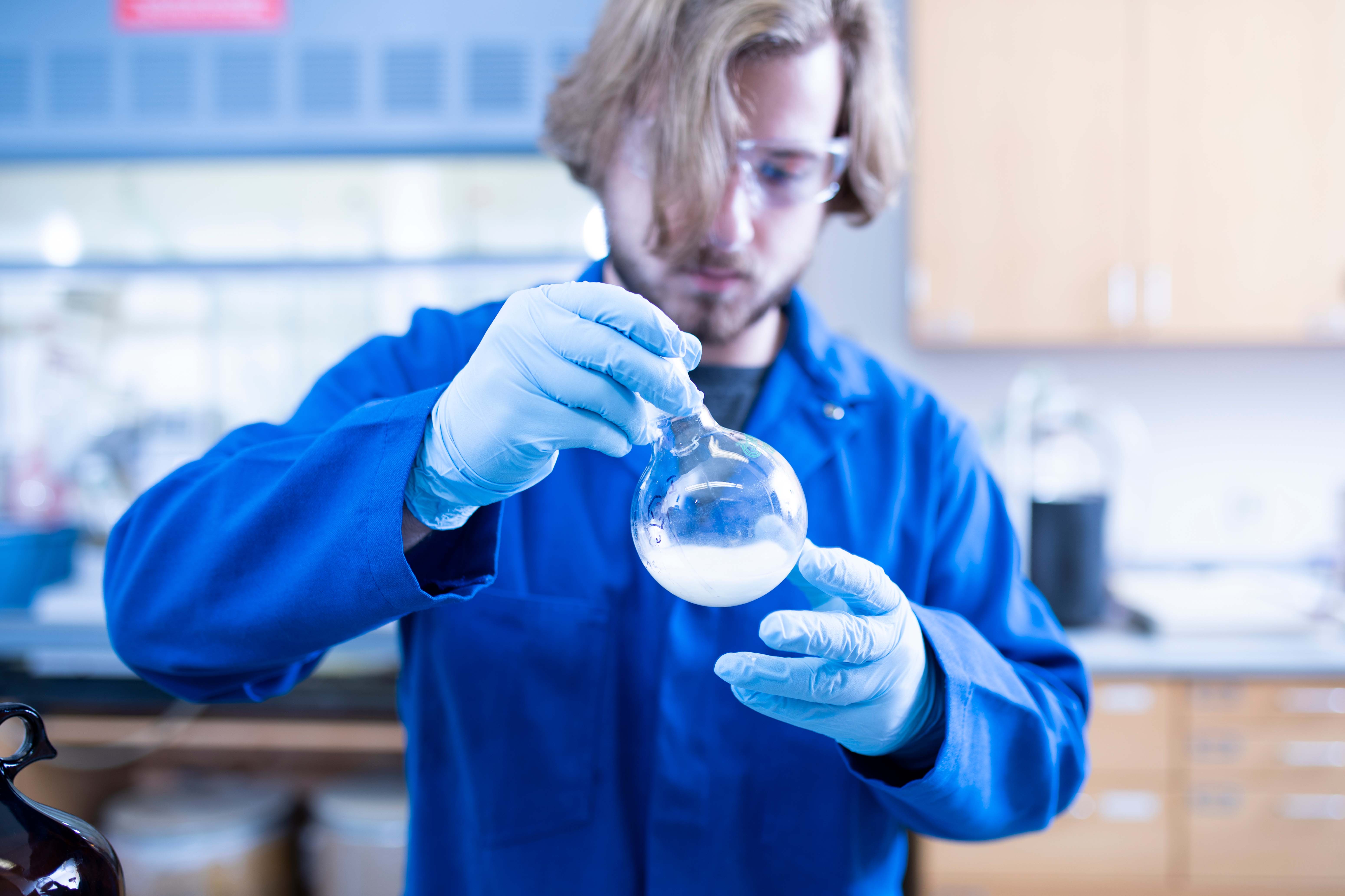 Student holding chemistry equipment up to look at it