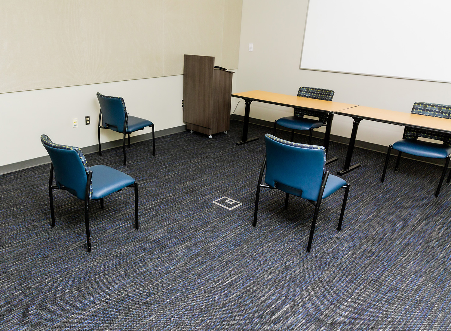 Meeting Room 104 view facing left with chairs, podium, and a whiteboard