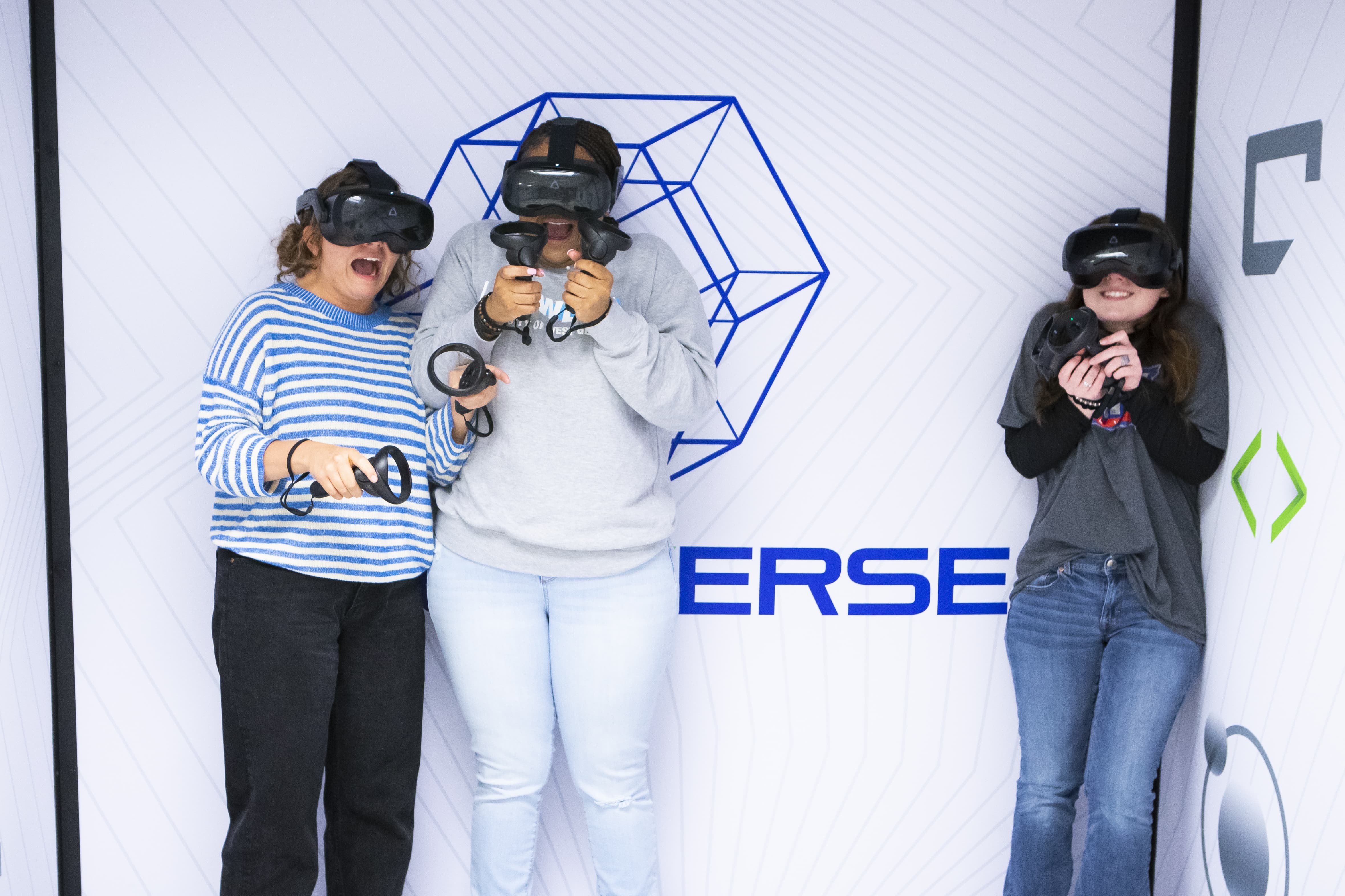 Three students look scared in a corner while playing VR.