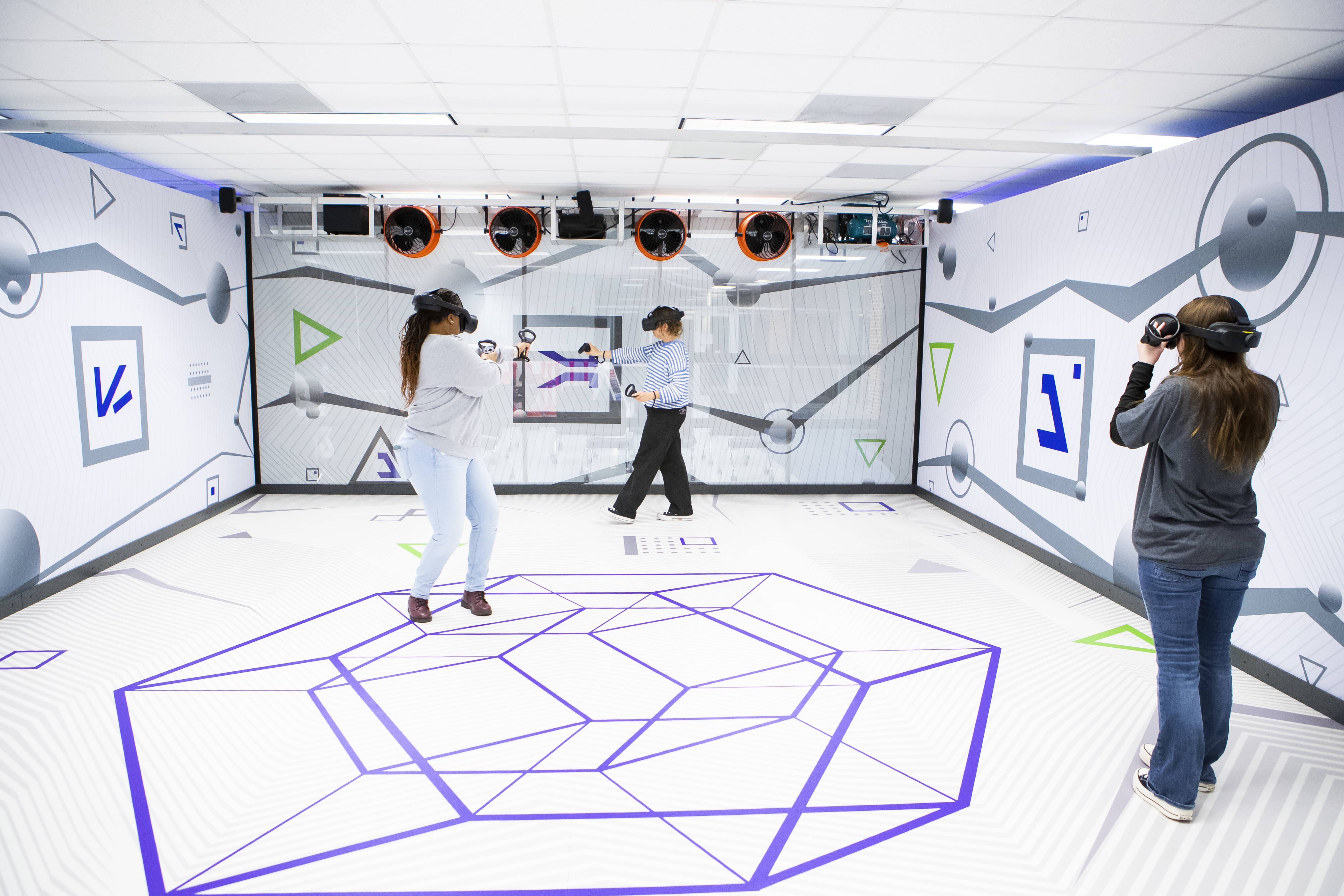 Three students playing a game in the Virtual Reality room.