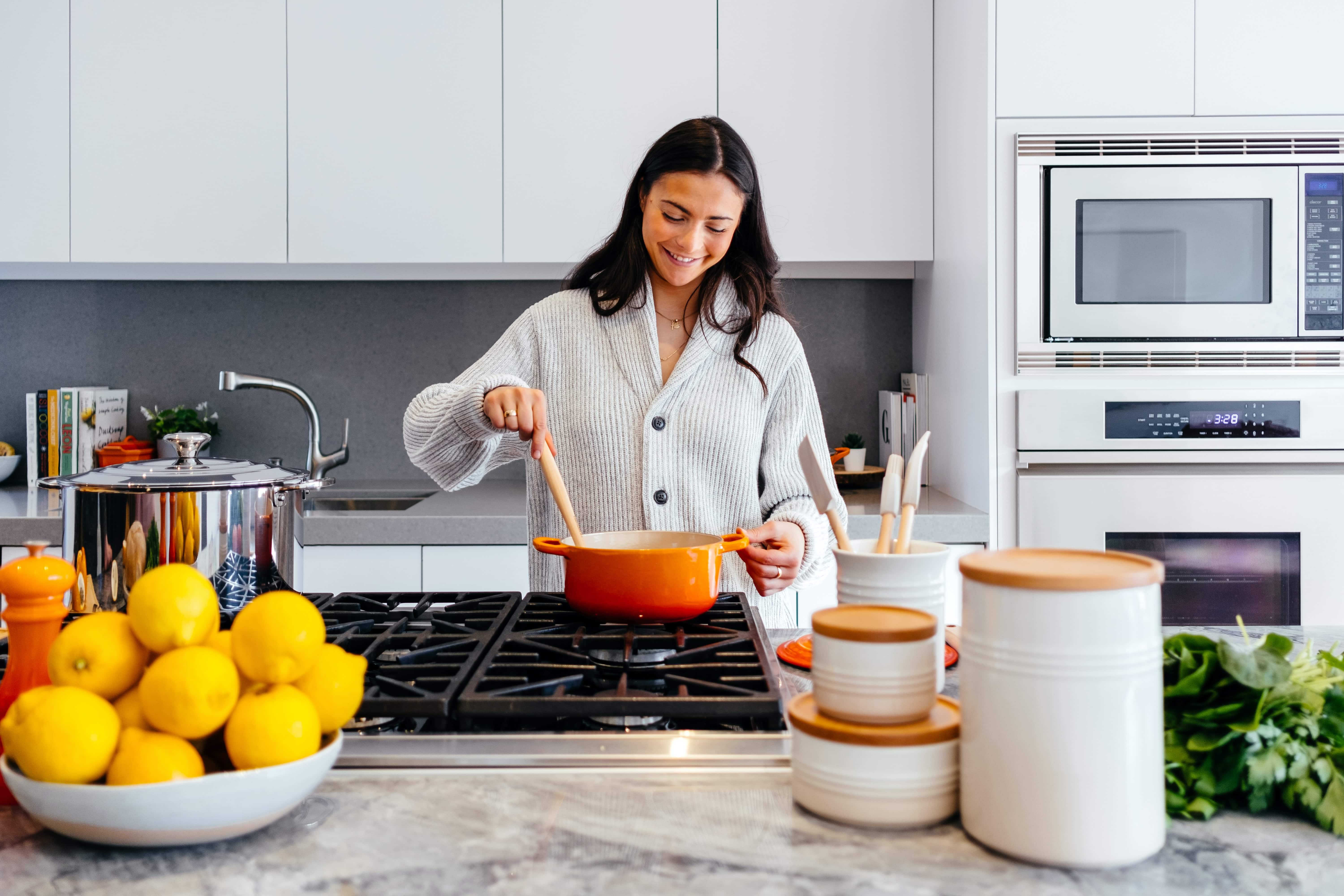 smiling female making food in a clean and well organized kitchen.