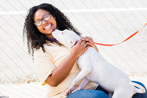 A young woman holding a dog