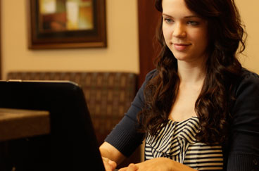 Woman sitting at home looking at her computer.